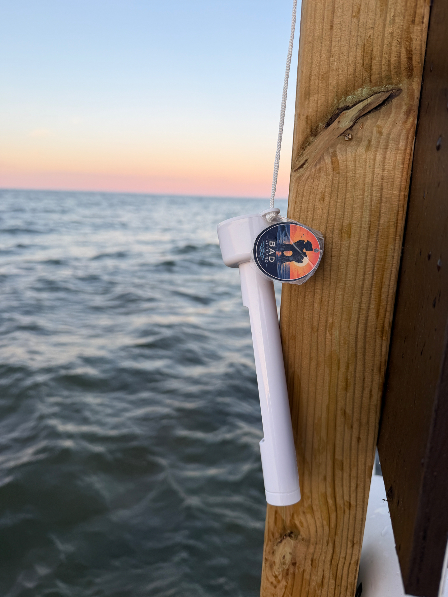 Bad Gotland-termometer som hänger vid havet i solnedgång